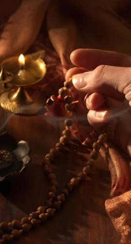 Devotee performing naam jaap with mala and sacred pooja items.
